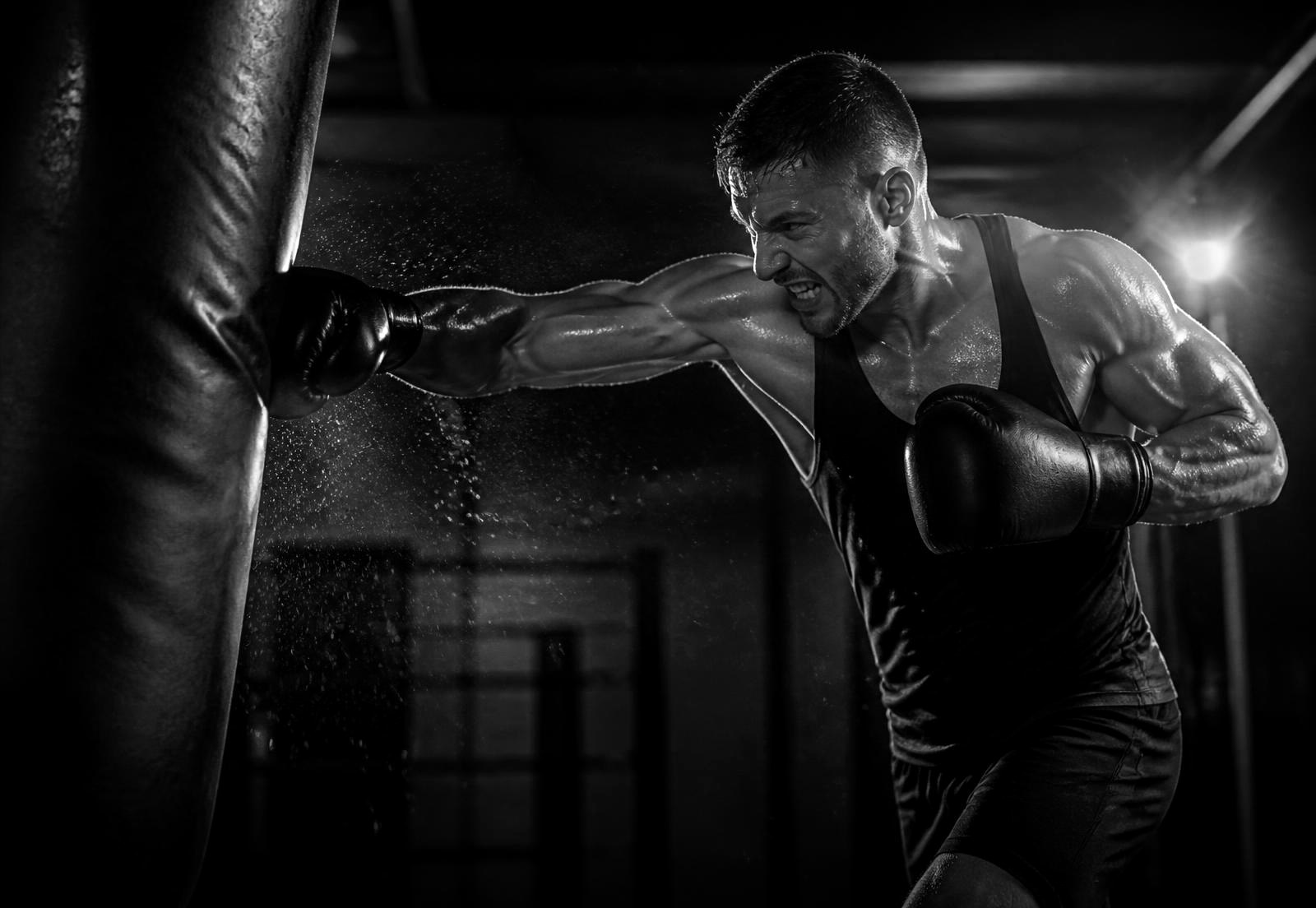 Boxer throwing an explosive punch into a heavy bag during a night training session